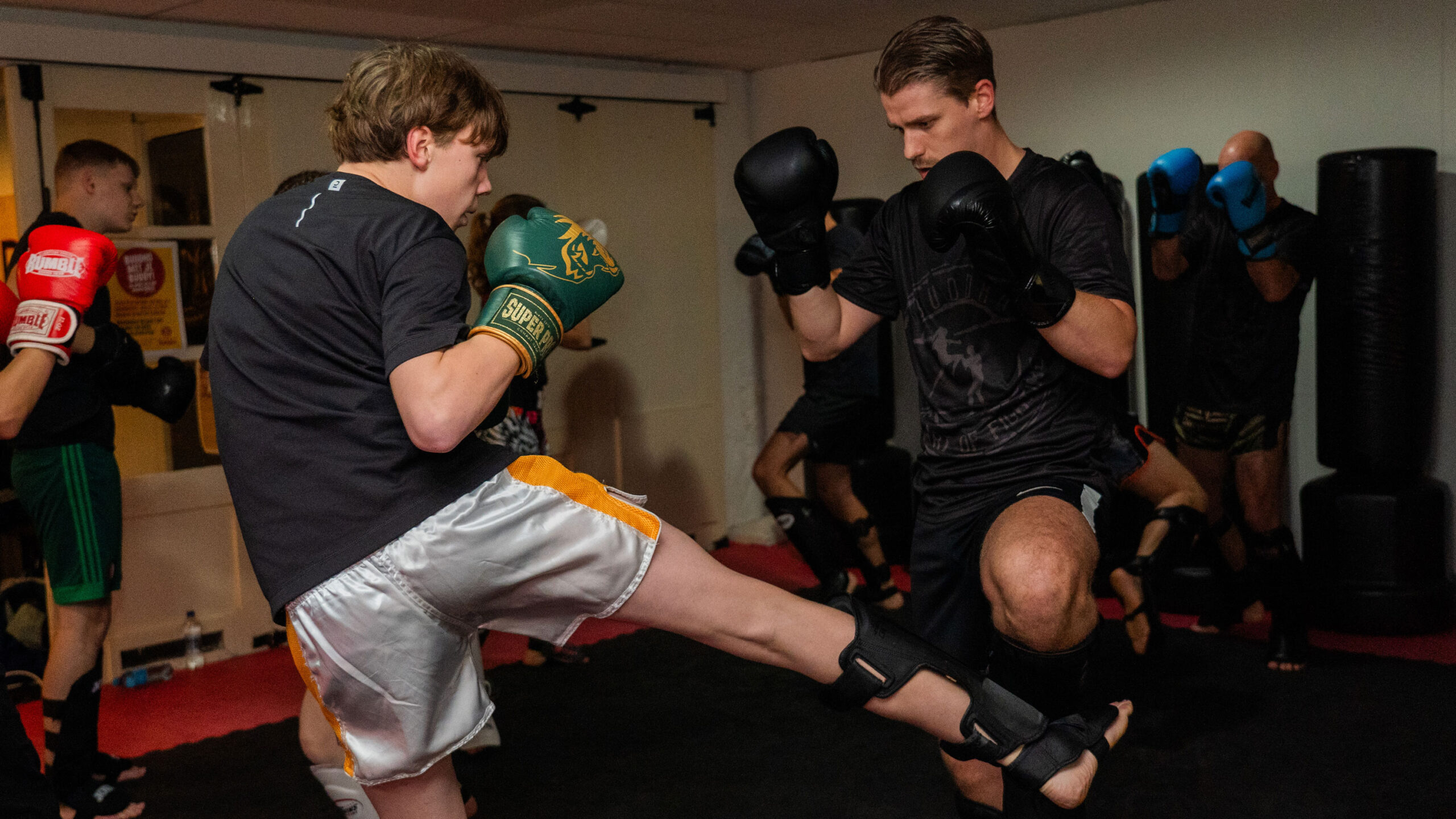 Sporters oefenen traptechnieken en timing tijdens een kickbokstraining.